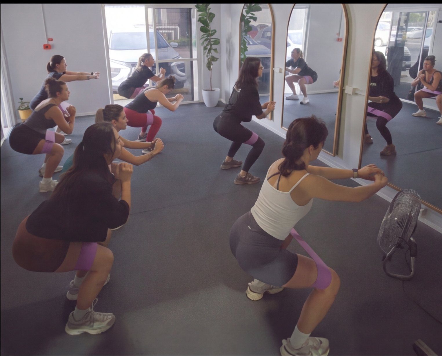 Group class doing banded squats in the studio