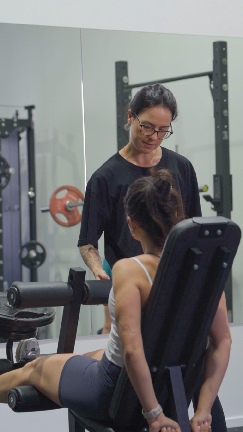 Mari coaching a member on the leg machine